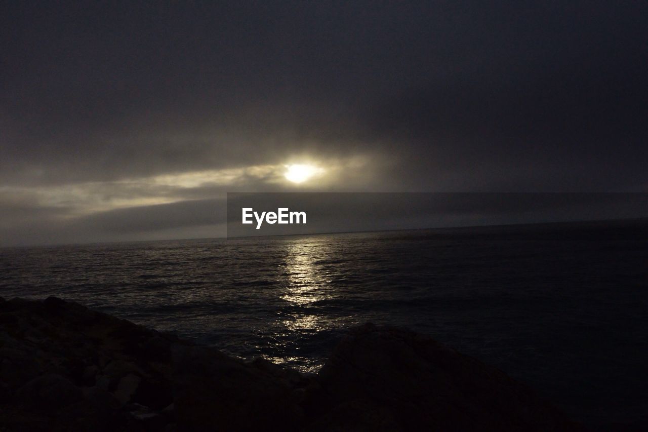 Idyllic view of sea during sunset against cloudy sky