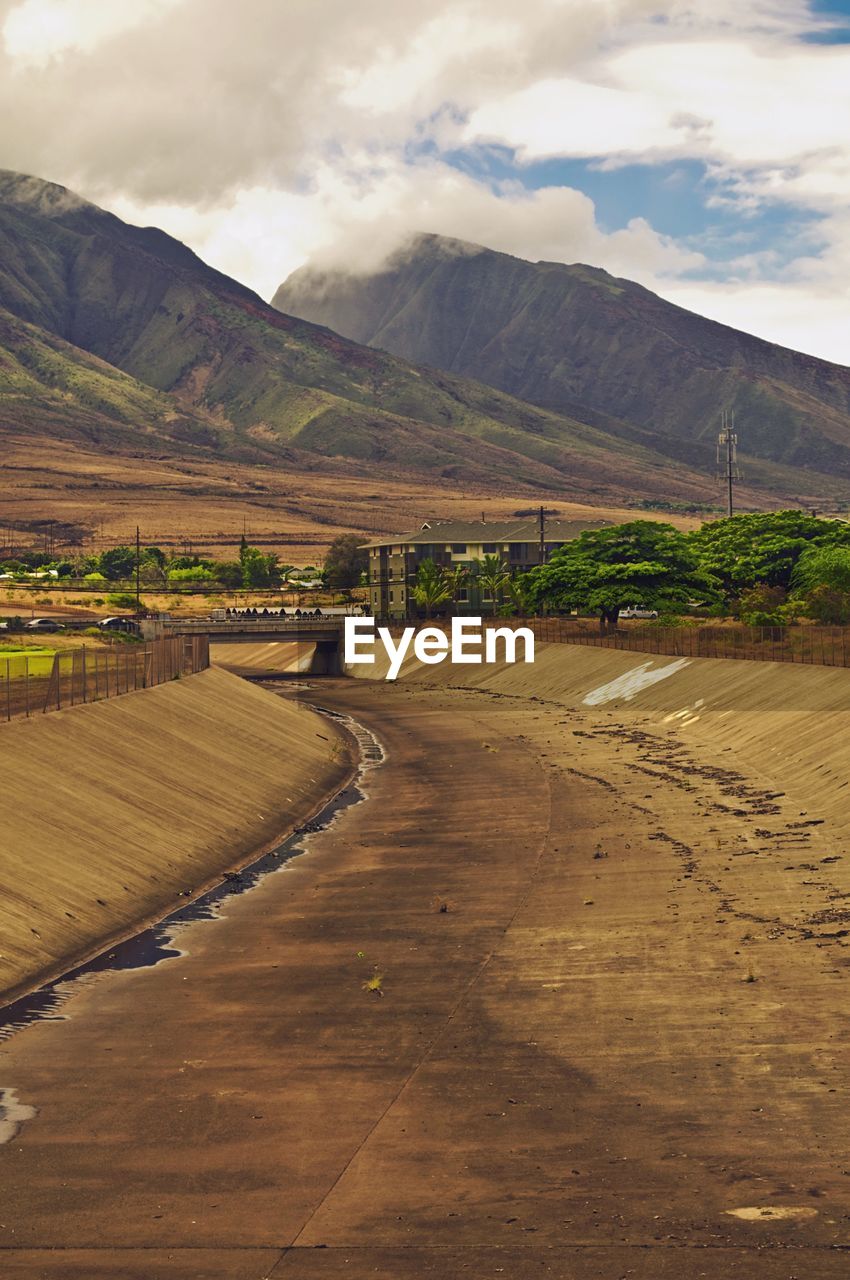 Sewer by mountains against cloudy sky