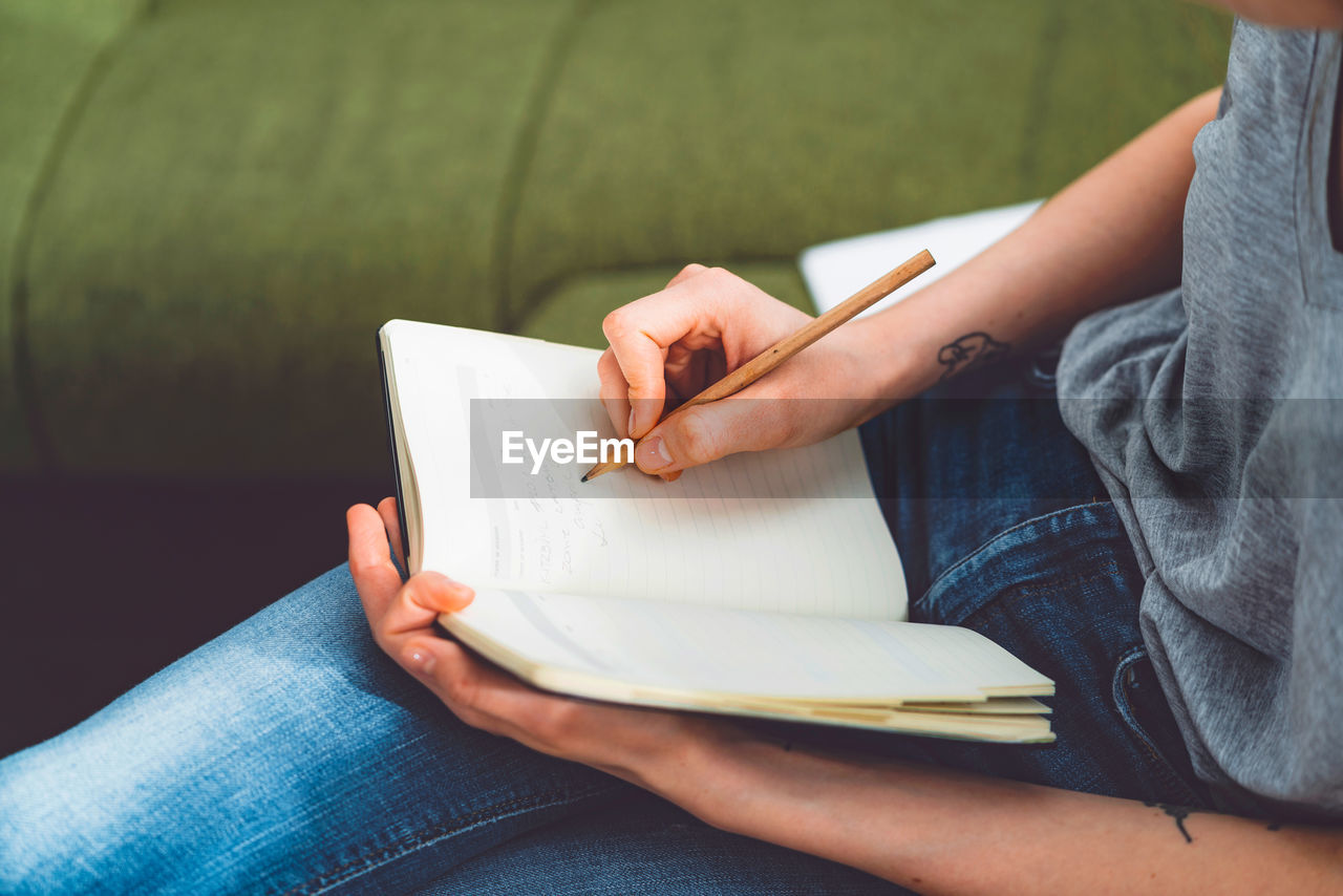 midsection of woman reading book at home