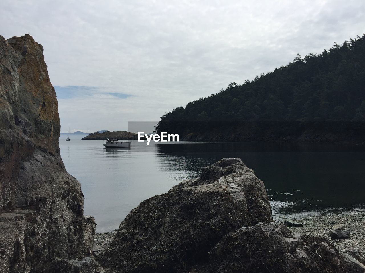 Rocky shore against cloudy sky