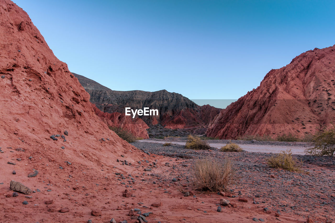 Scenic view of arid landscape against clear blue sky