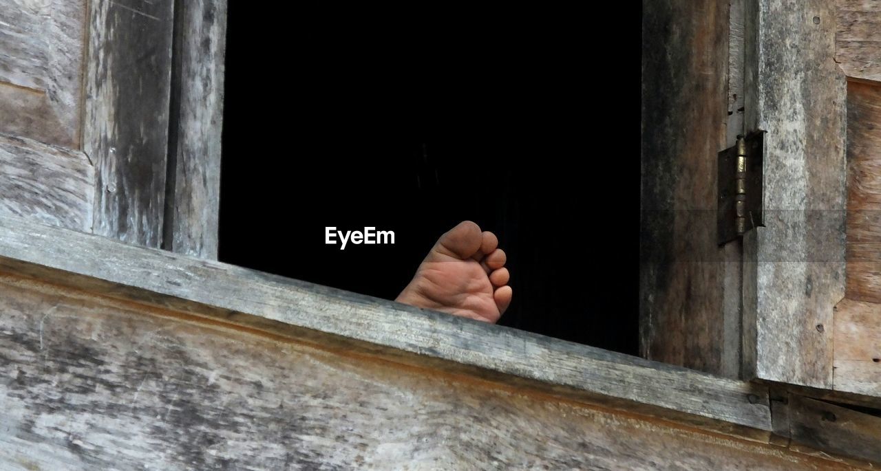 Close-up of person soles of the feet on window of house