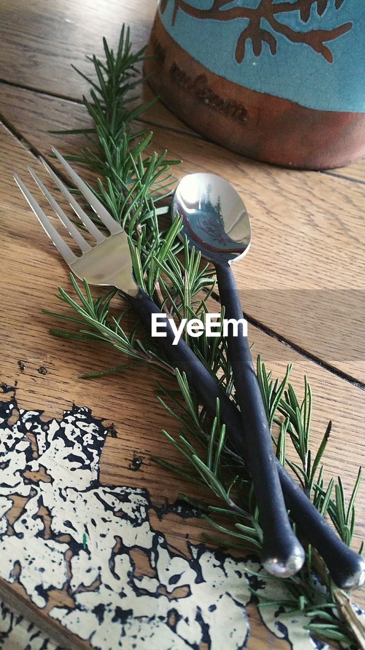 Close-up of spoon and fork with leaves on table