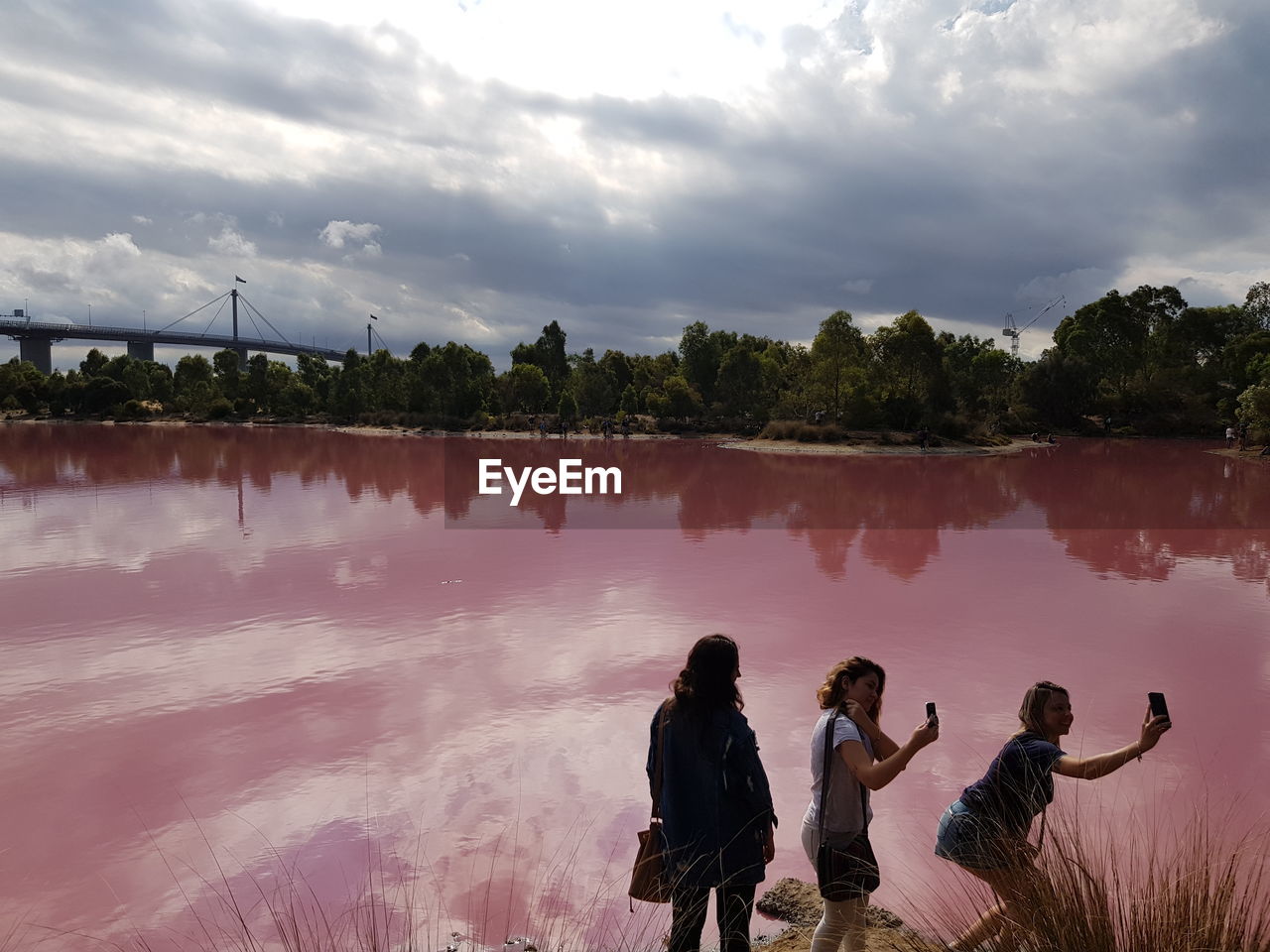 REAR VIEW OF PEOPLE STANDING BY LAKE