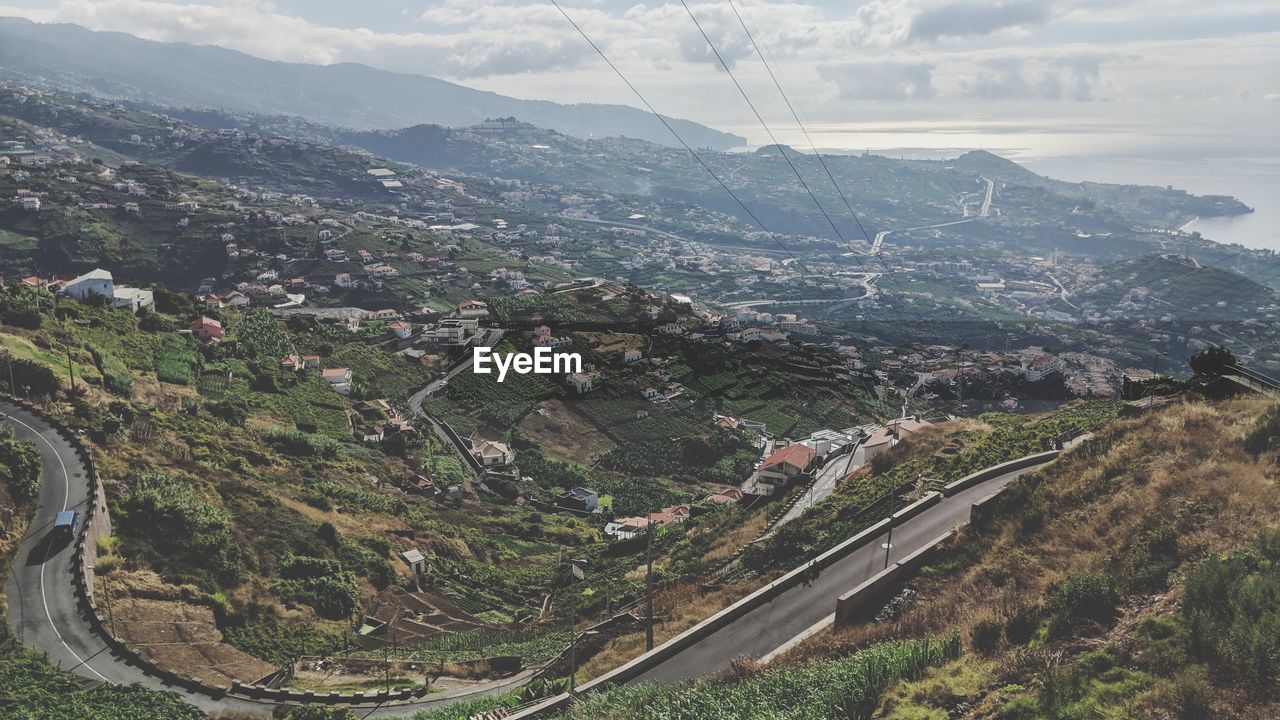 HIGH ANGLE VIEW OF ROAD BY BUILDINGS IN CITY