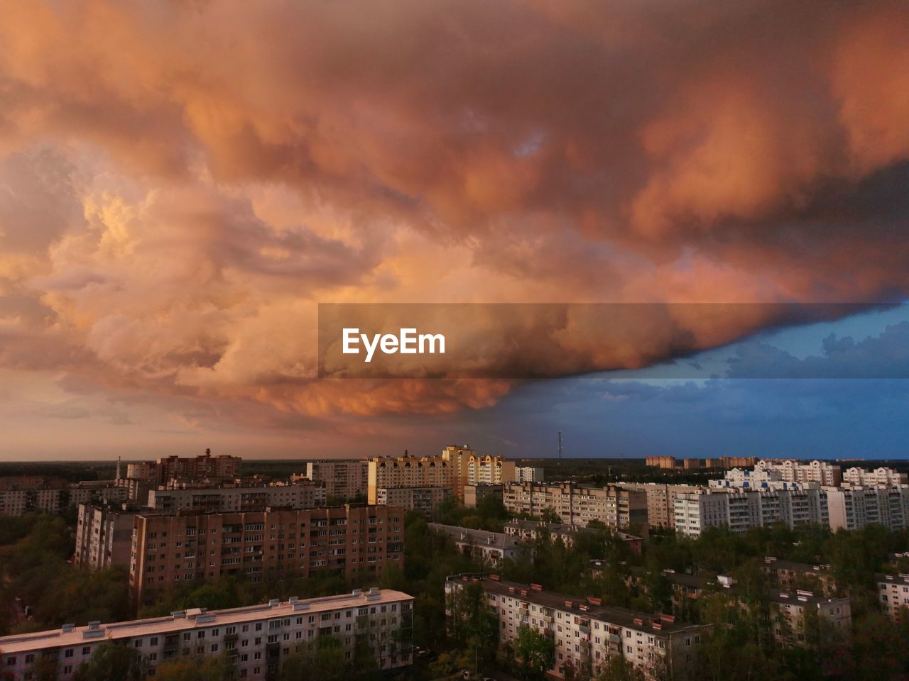 Buildings in city against dramatic sky during sunset