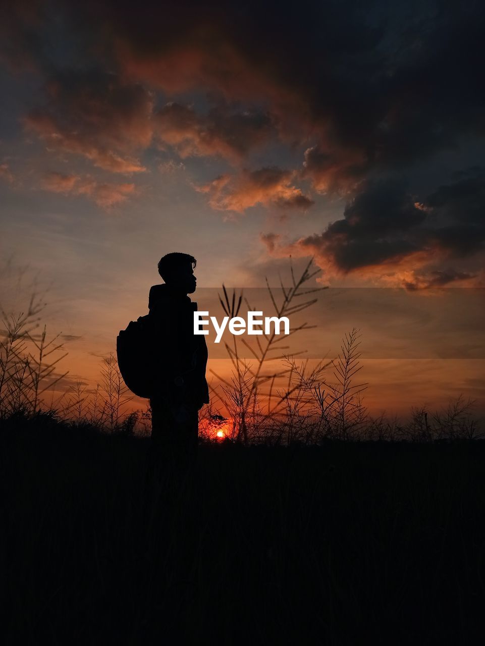 SILHOUETTE MAN STANDING ON FIELD DURING SUNSET