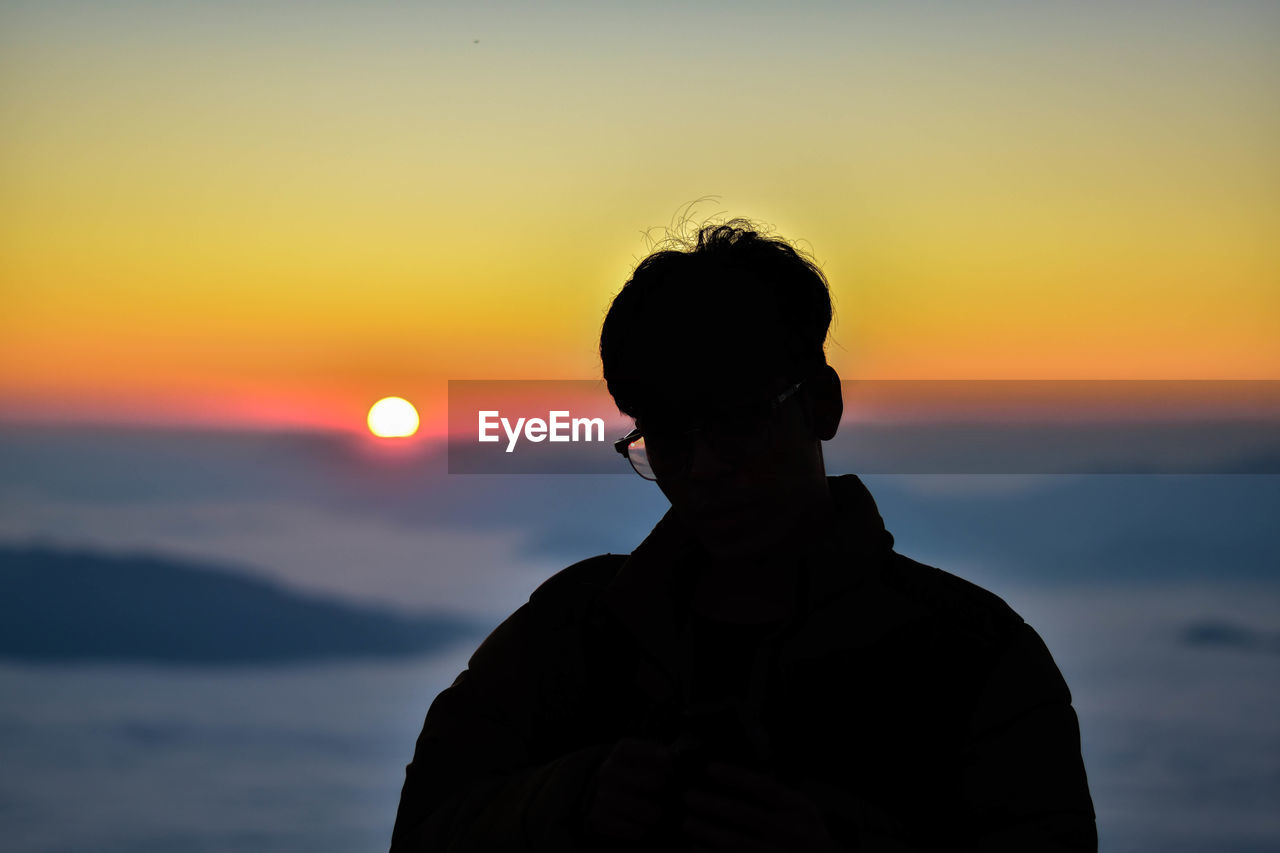 Silhouette man standing against sky during sunset