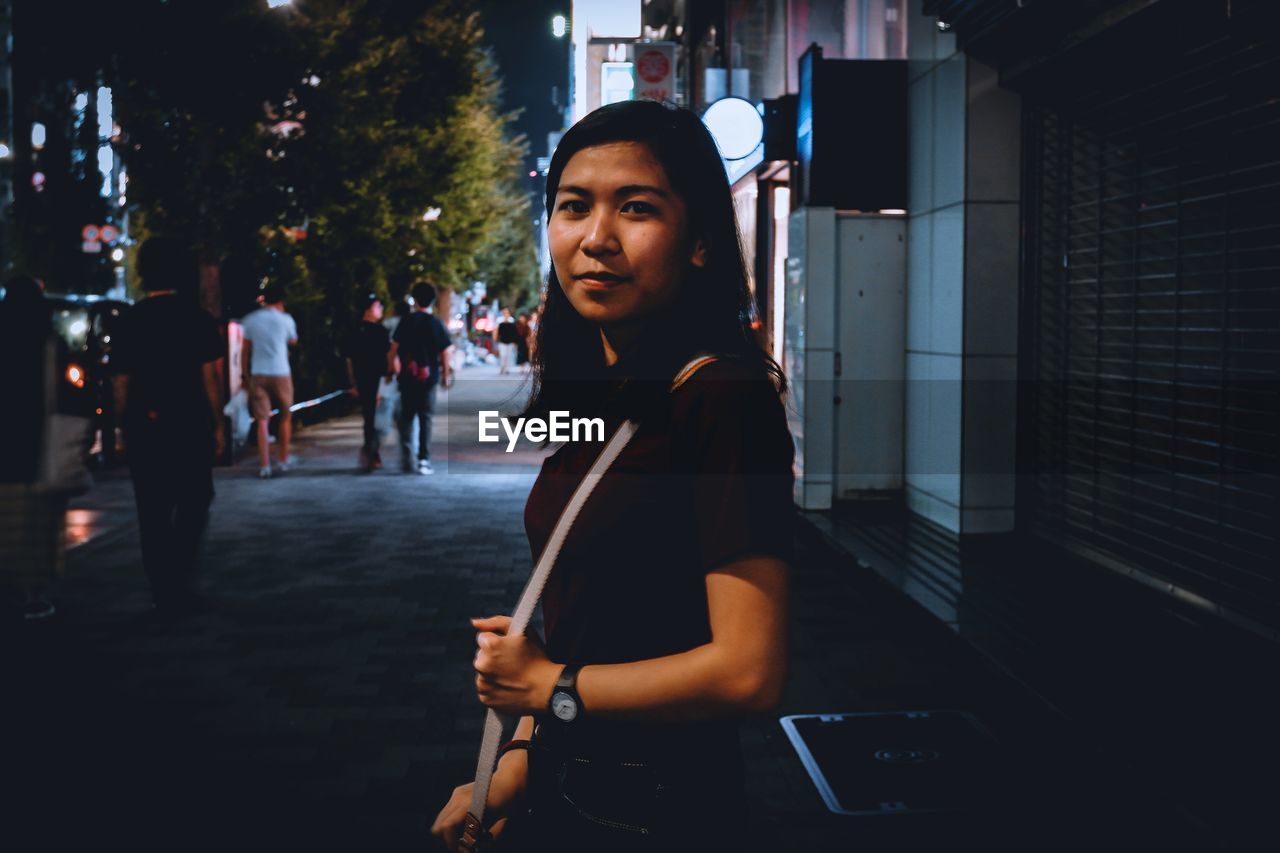 Portrait of woman standing in city at night