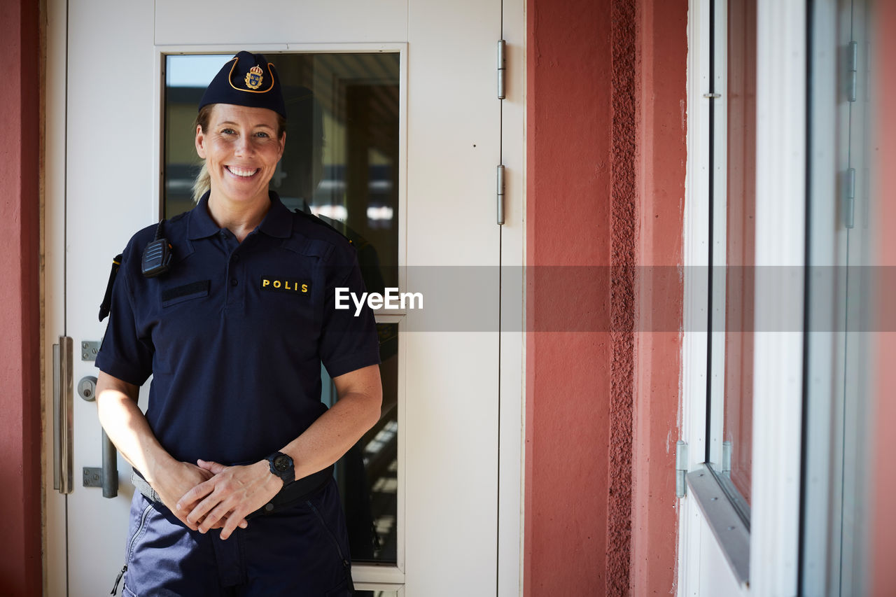 Portrait of smiling policewoman standing outside police station