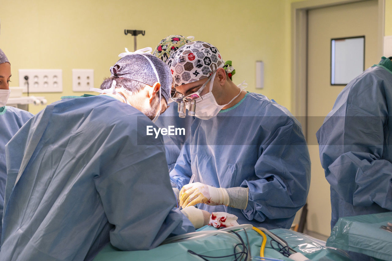 Surgeons performing surgery on patient in operating room