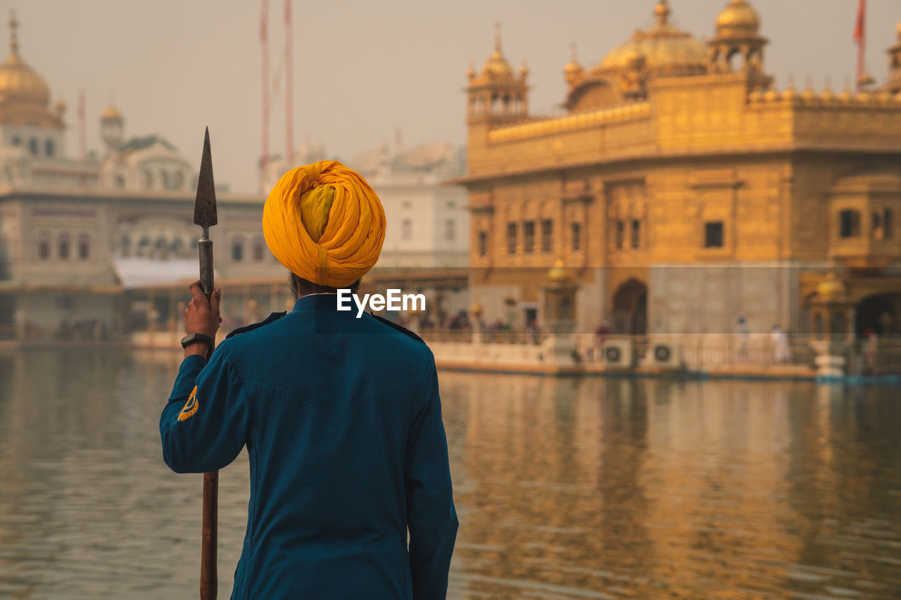 Rear view of man standing in city against the golden temple