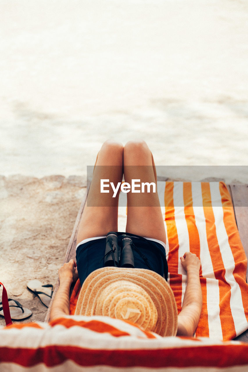 Low section of woman lying on sand at beach