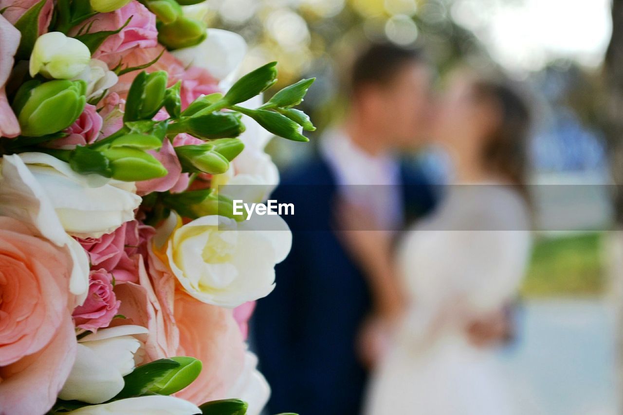 Close-up of rose bouquet with couple in background