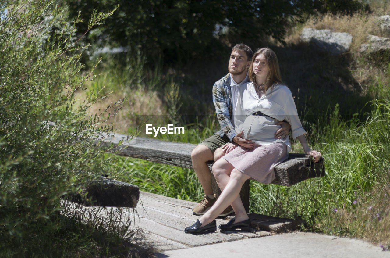 Full length of couple standing on bridge by trees