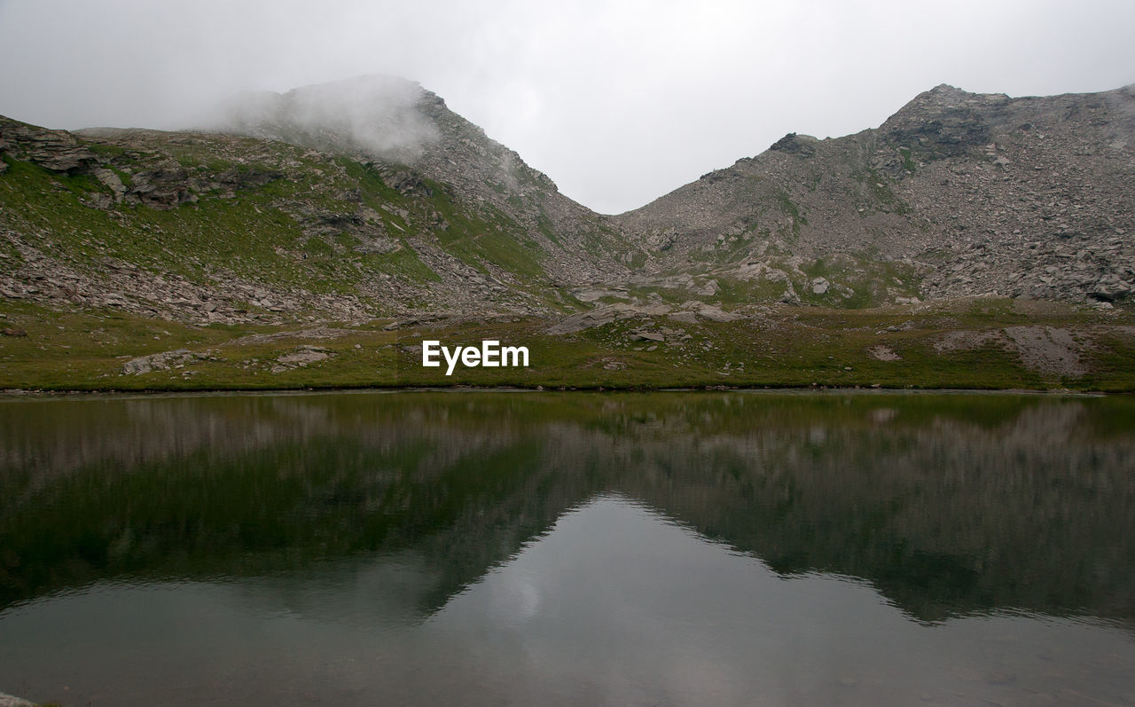 Scenic view of lake by mountains against sky