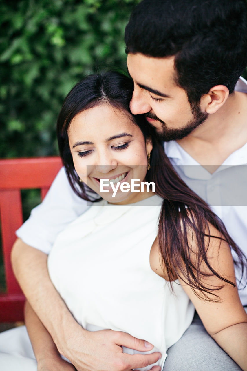 Close-up of couple romancing while relaxing on bench at park