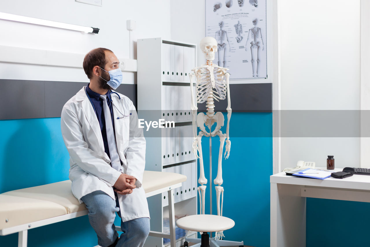 Doctor wearing mask sitting in clinic