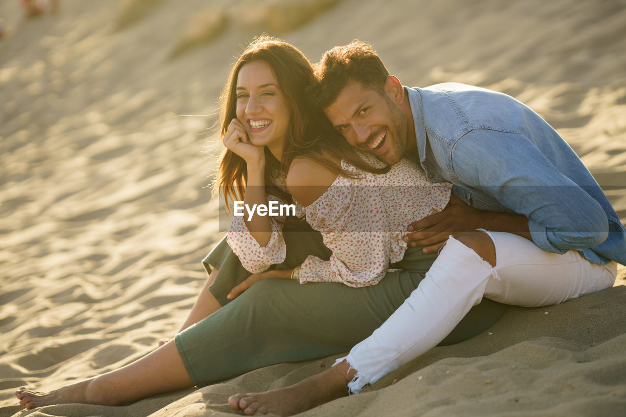 Laughing young couple sitting on beach