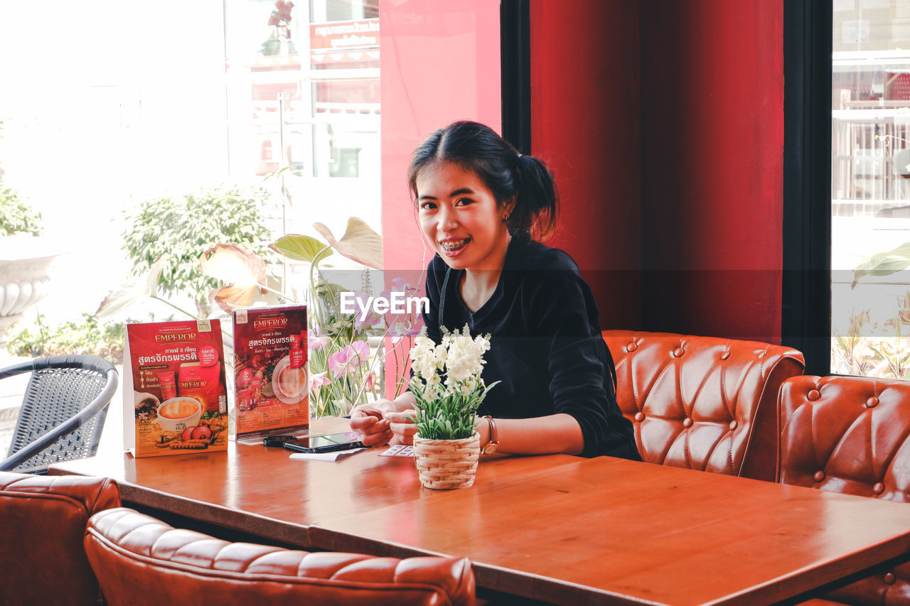 Portrait of woman sitting on table in restaurant