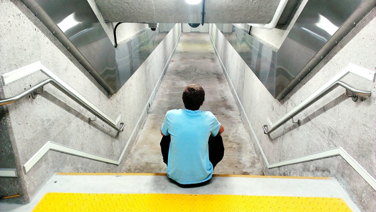 Rear view of man sitting on staircase