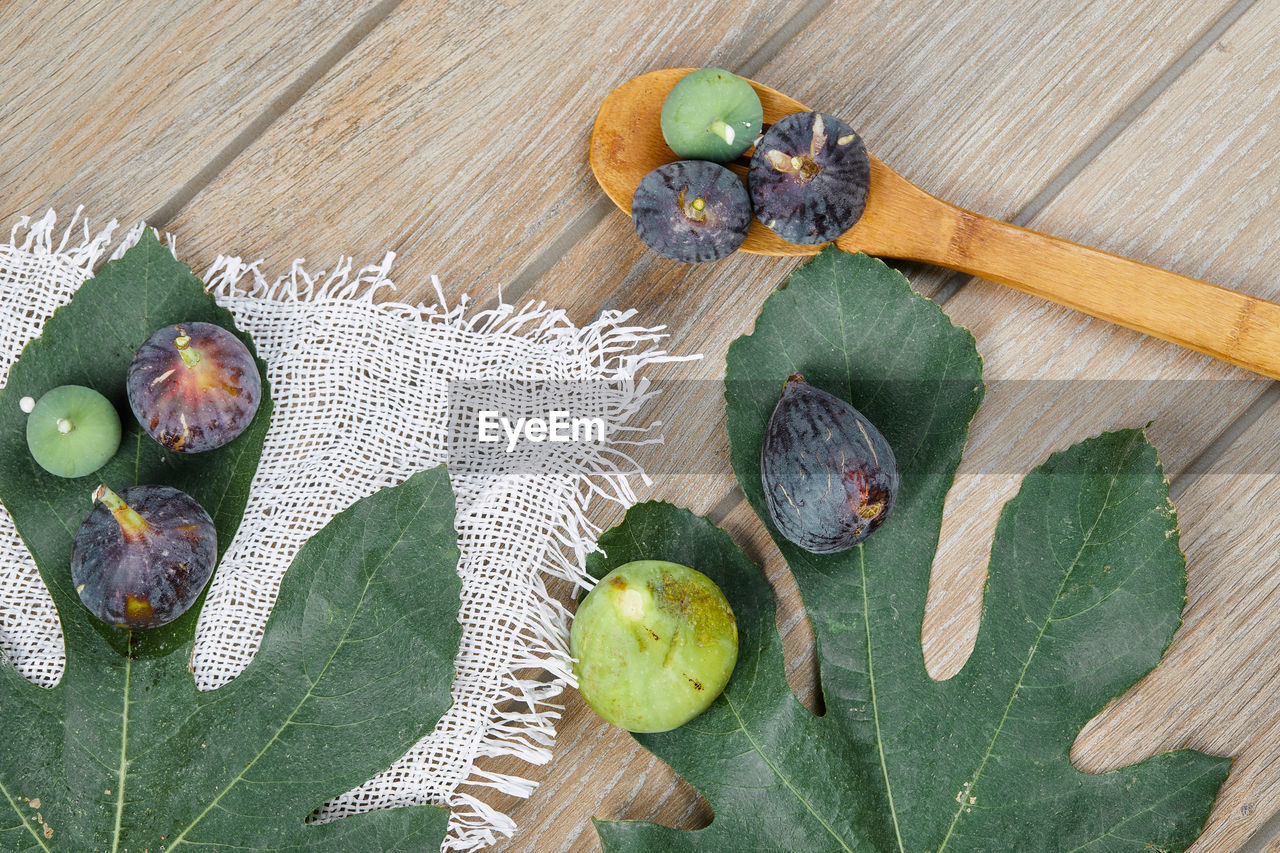 HIGH ANGLE VIEW OF FRUITS AND LEAVES ON WOODEN TABLE