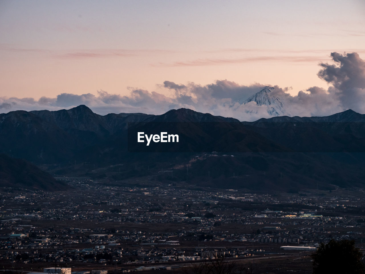 AERIAL VIEW OF TOWNSCAPE BY MOUNTAIN AGAINST SKY