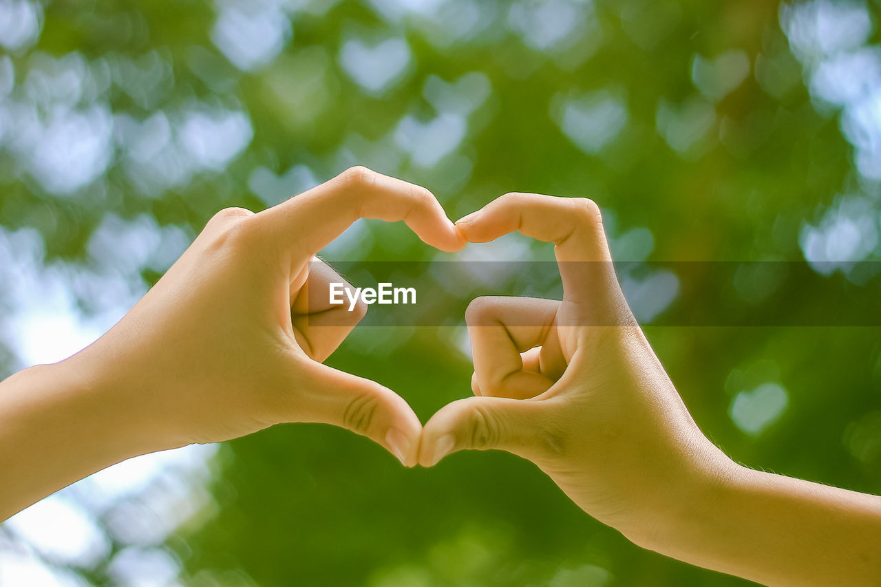 Cropped image of friends making heart shape with hands