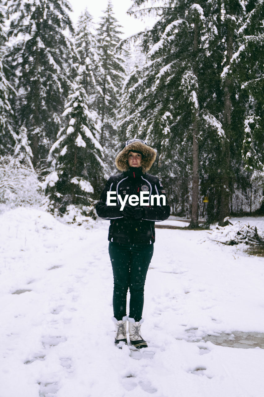 Portrait of woman in warm clothes standing on snowfield