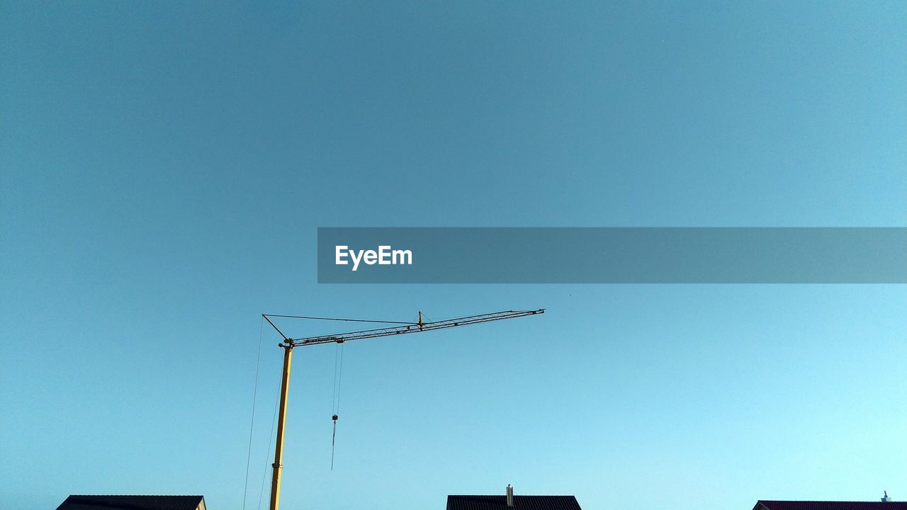 LOW ANGLE VIEW OF CRANES AGAINST CLEAR BLUE SKY