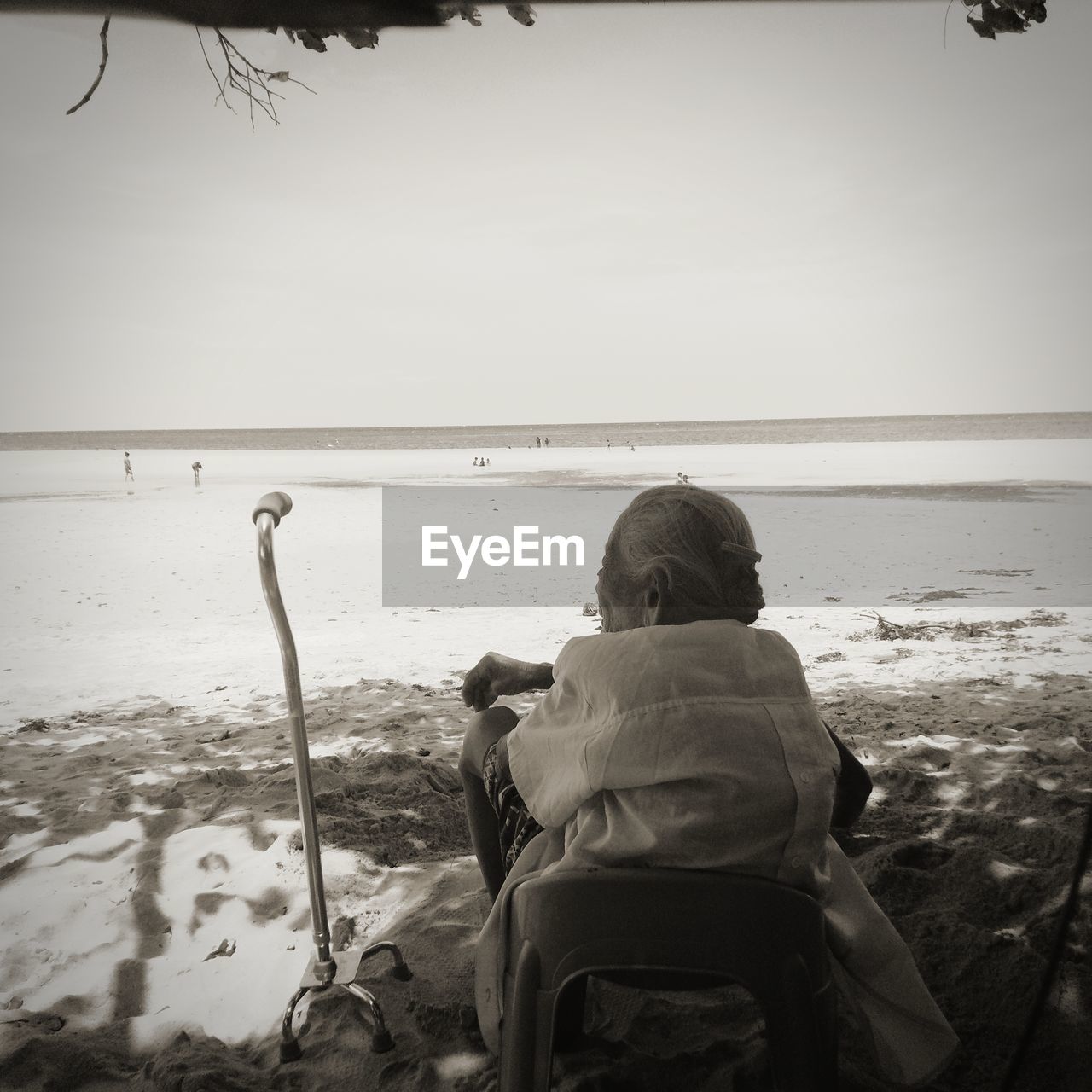 Rear view of senior woman sitting at beach