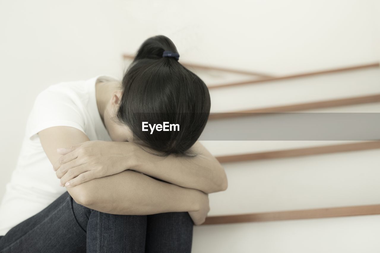 The depression woman alone sitting on staircase she thought so much and headaches, eye pain.
