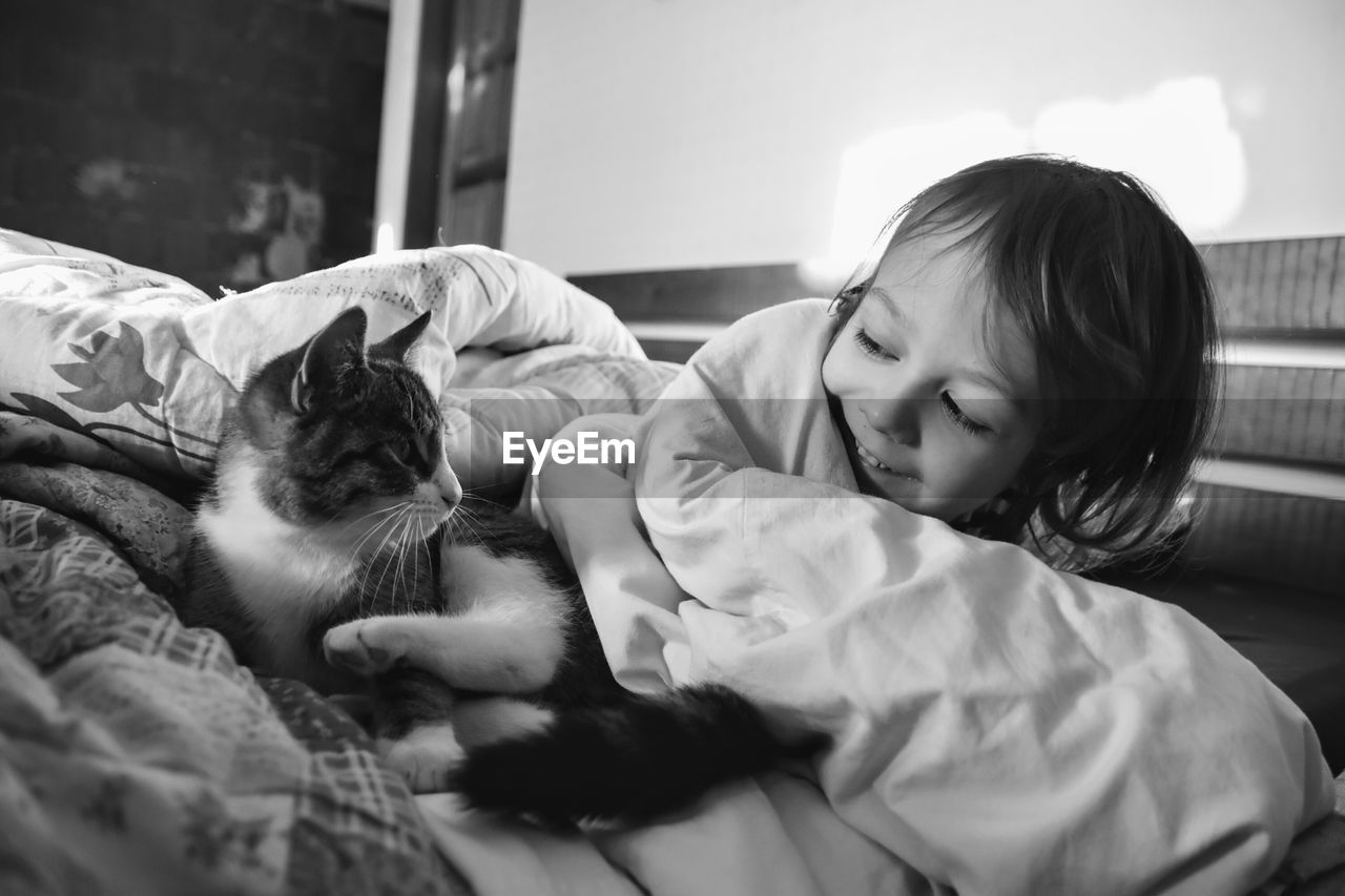 Boy sleeping with cat on bed at home
