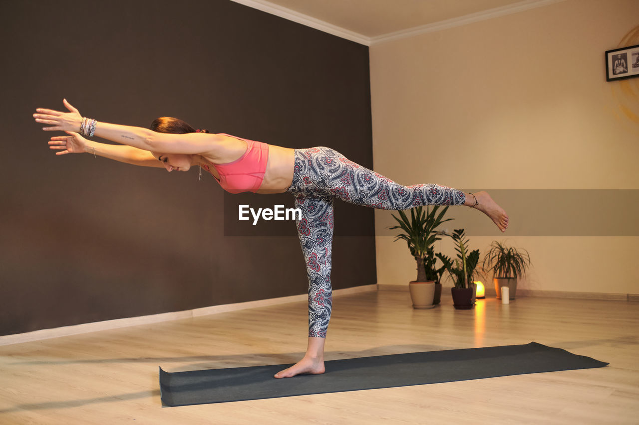 Young woman doing yoga on yoga mat in atmospheric yoga studio