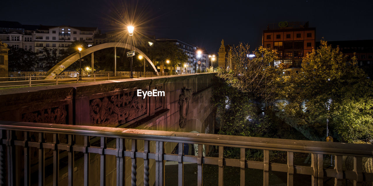 ILLUMINATED BRIDGE OVER CANAL BY BUILDING AT NIGHT