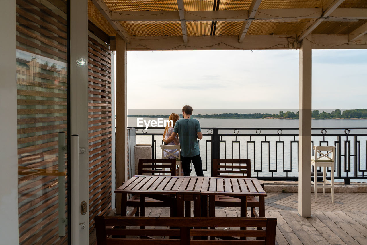 Unrecognizable young couple resting near the river at terrace of street cafe