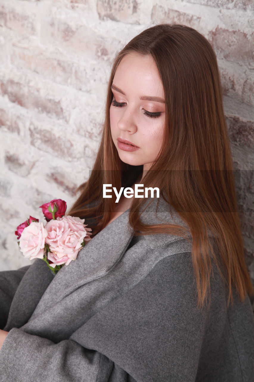Fashion model wearing warm woolen gray coat decorated with pink  roses, spring floral theme