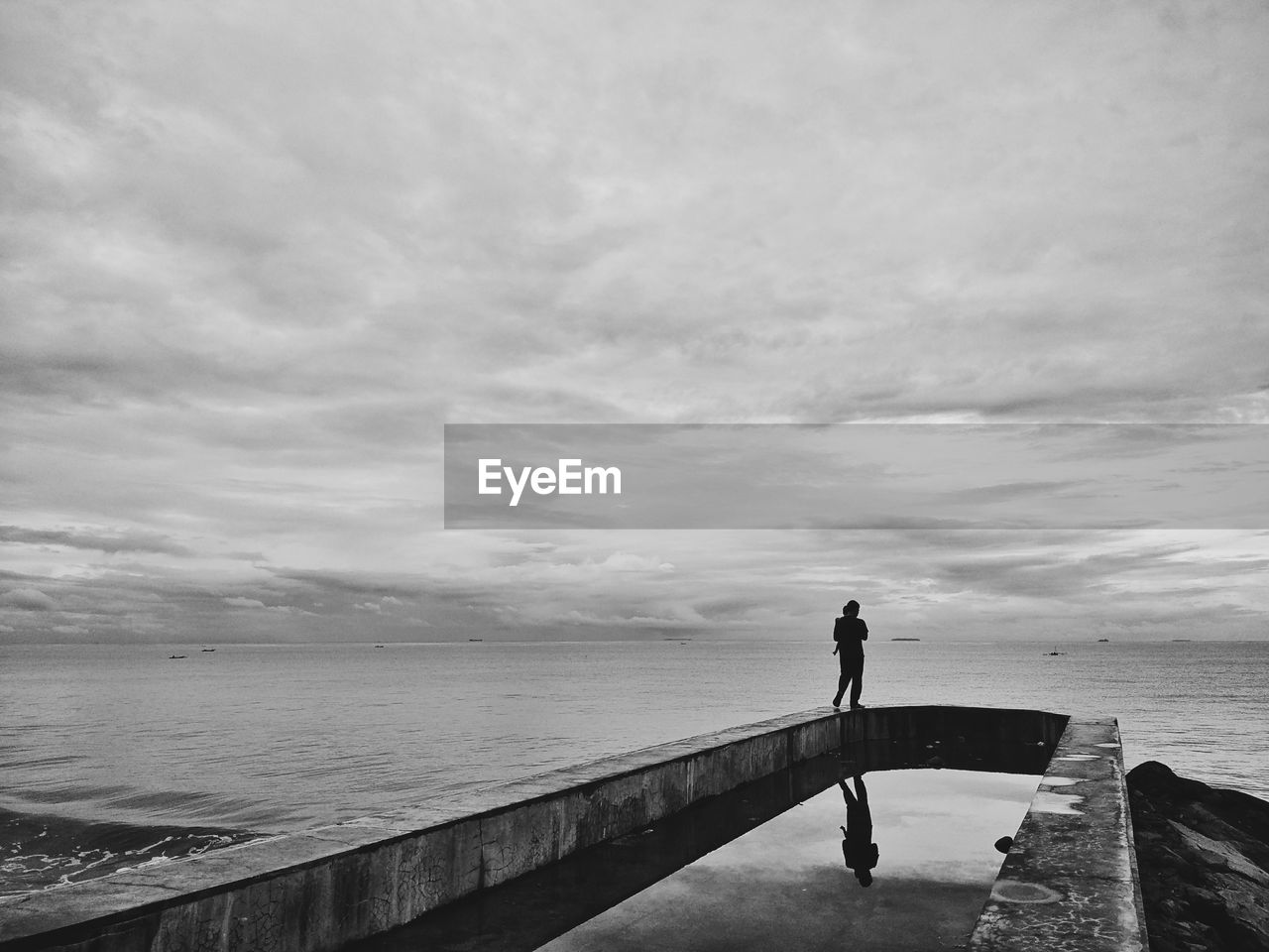 Rear view of person standing by sea against sky