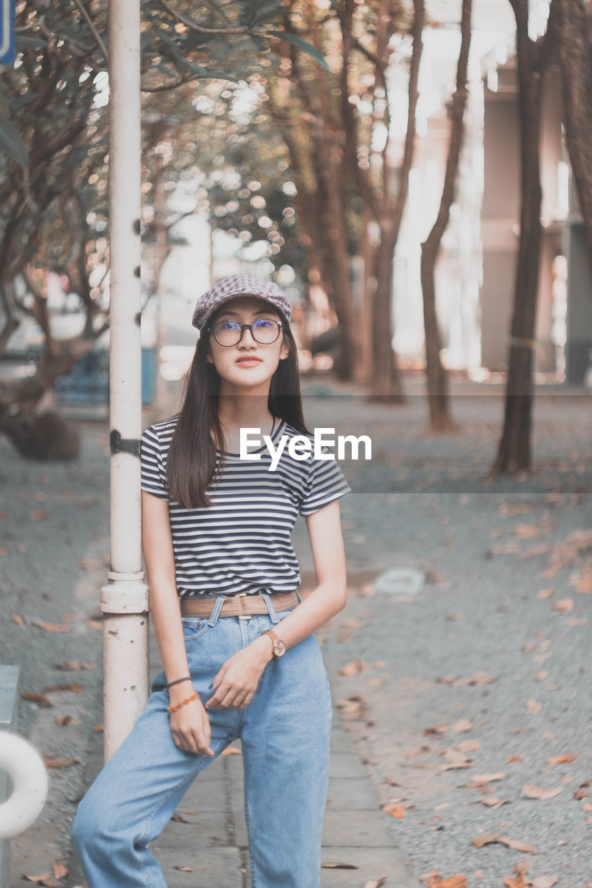 Portrait of young woman standing against trees