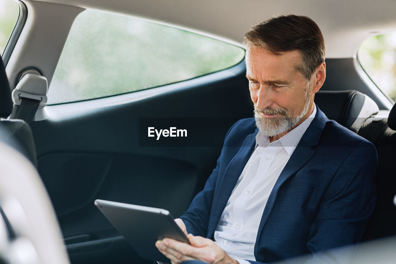 Man using digital tablet while sitting in car