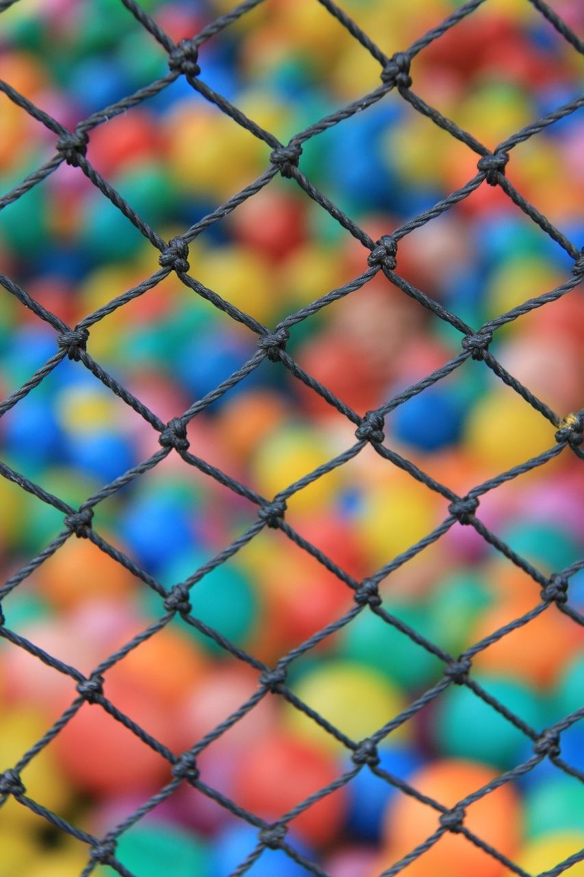 View of colorful balls through chainlink fence