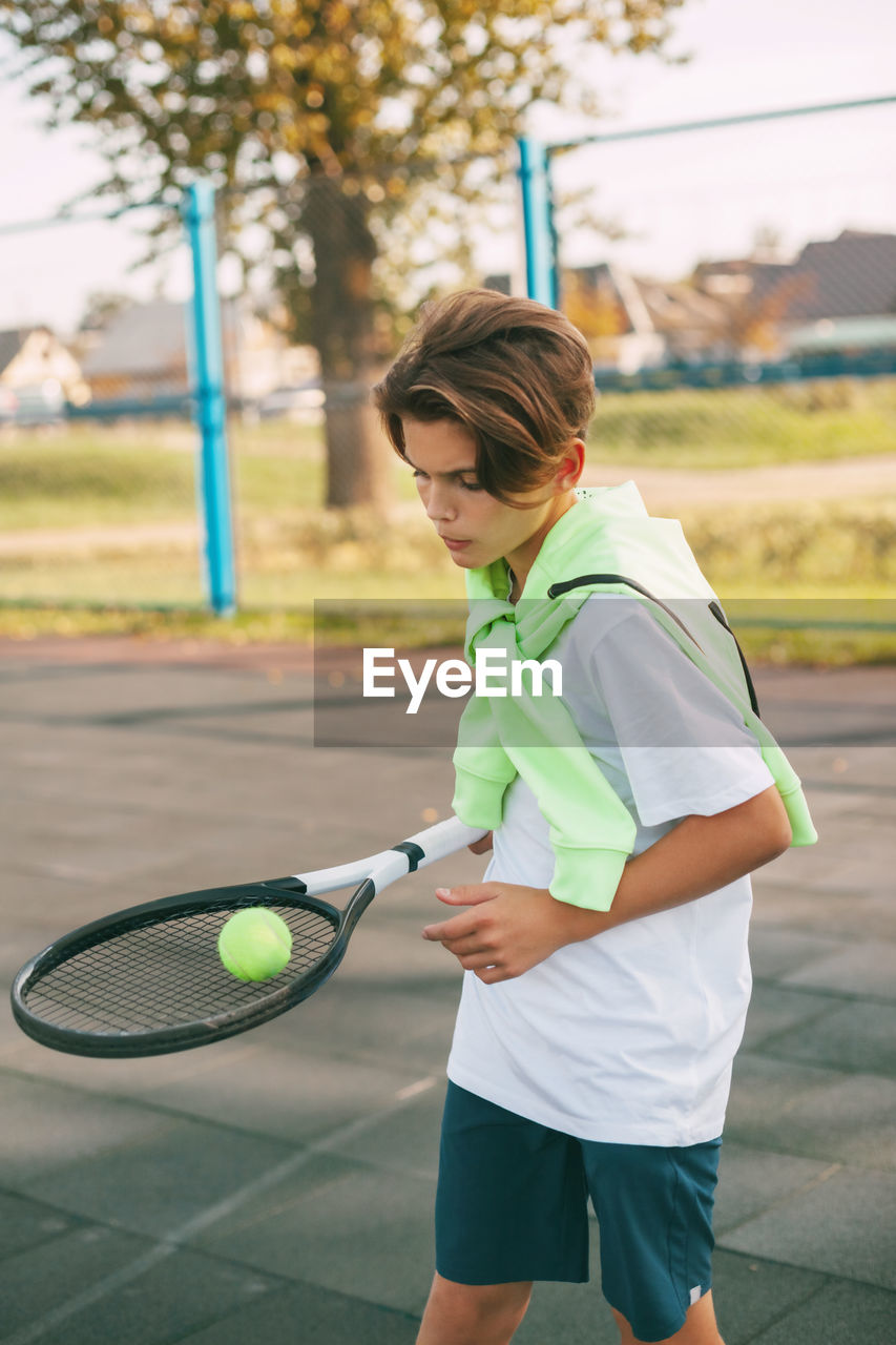 Boy playing tennis in court