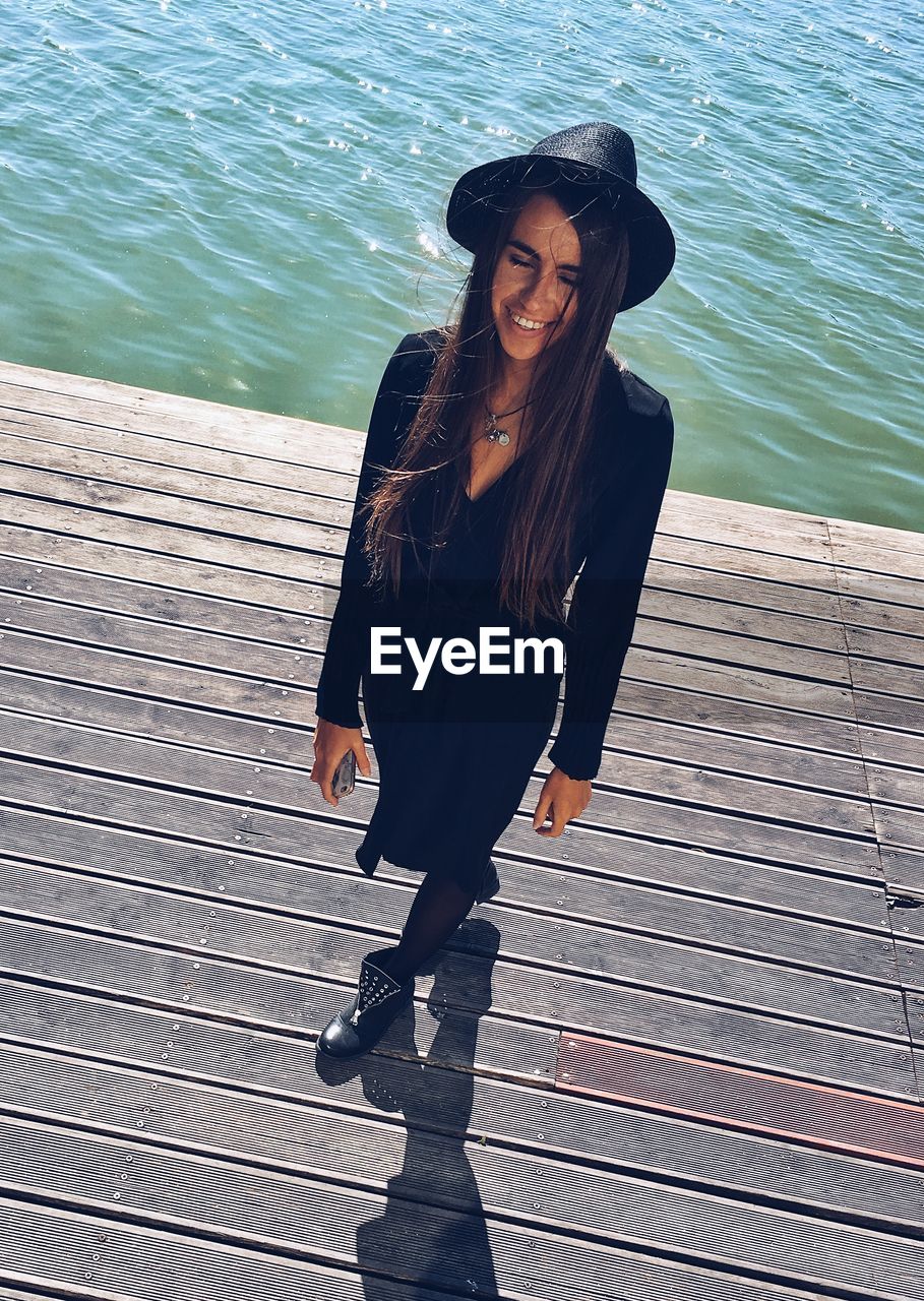 Full length of woman standing on pier over lake