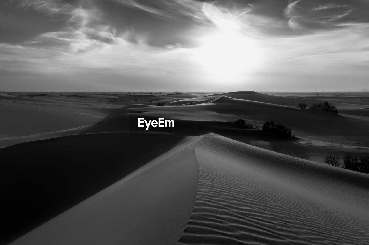 sky, scenics - nature, black and white, land, landscape, environment, cloud, monochrome, sand, nature, sand dune, beauty in nature, monochrome photography, horizon, white, desert, travel, tranquility, travel destinations, no people, water, tranquil scene, sunlight, non-urban scene, dune, outdoors, black, sea, sun, natural environment, beach, transportation, horizon over land, tourism, dramatic sky, remote, day, sunset