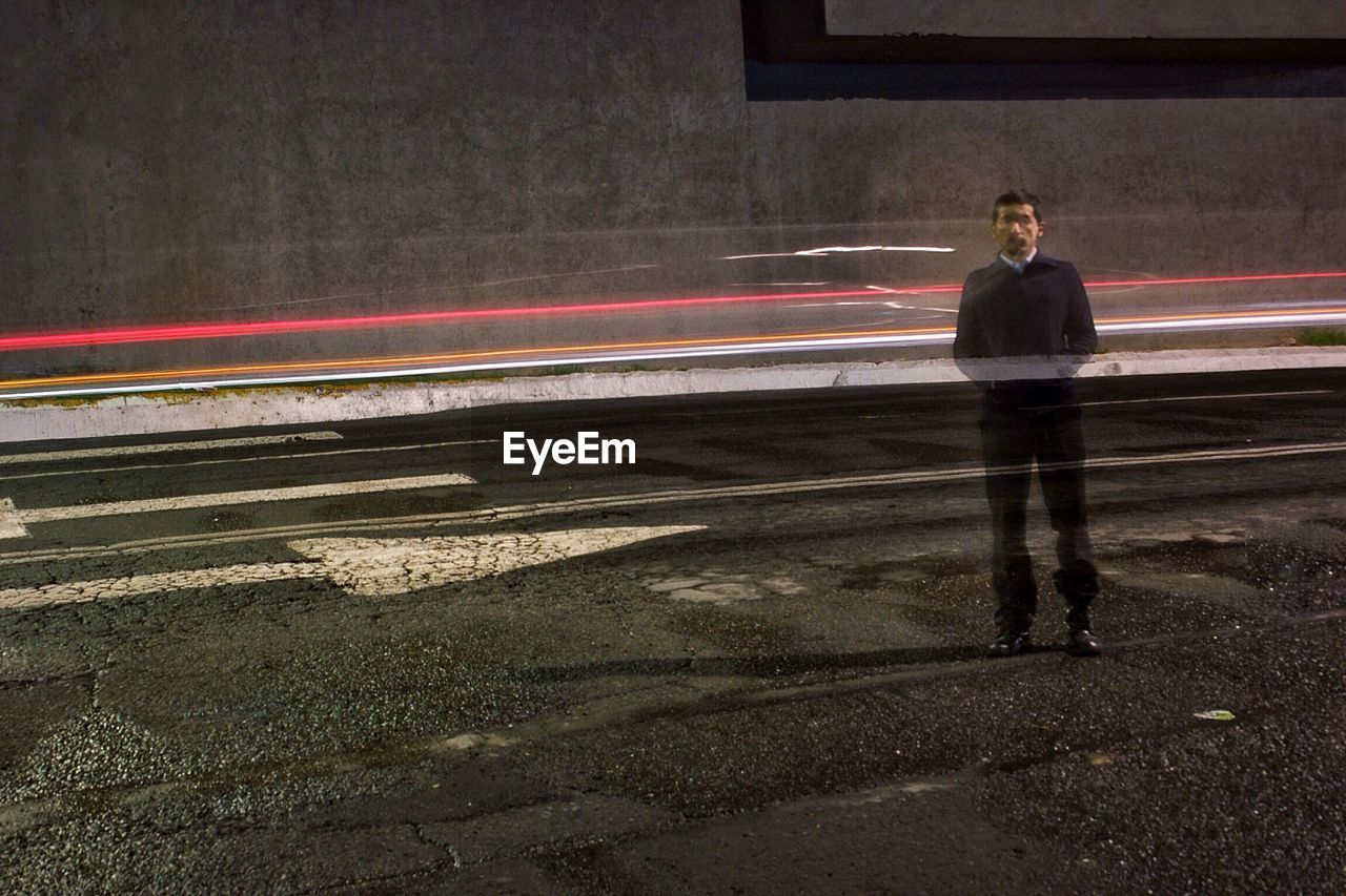 BLURRED MOTION OF WOMAN WALKING ON ROAD AT NIGHT