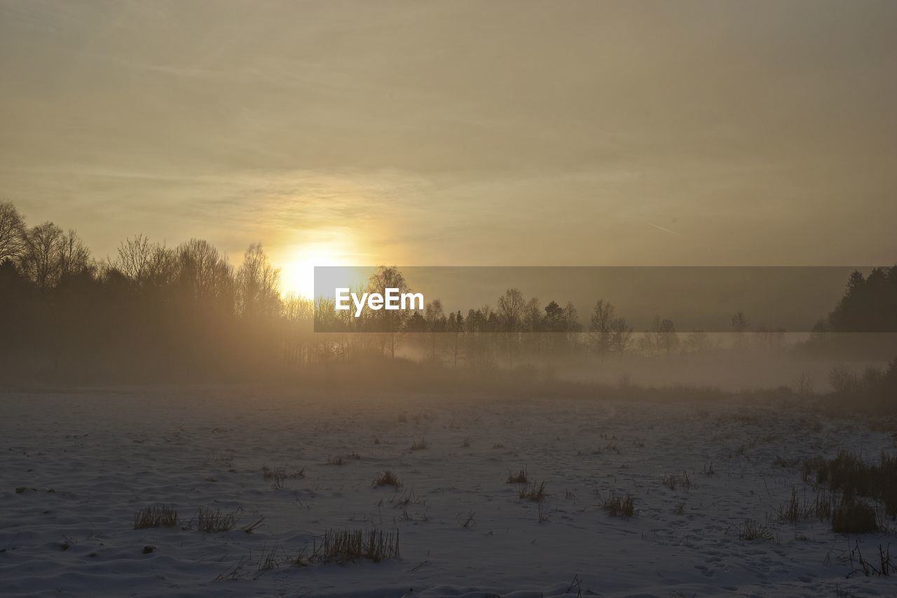 SNOW COVERED LANDSCAPE AGAINST SKY DURING SUNSET