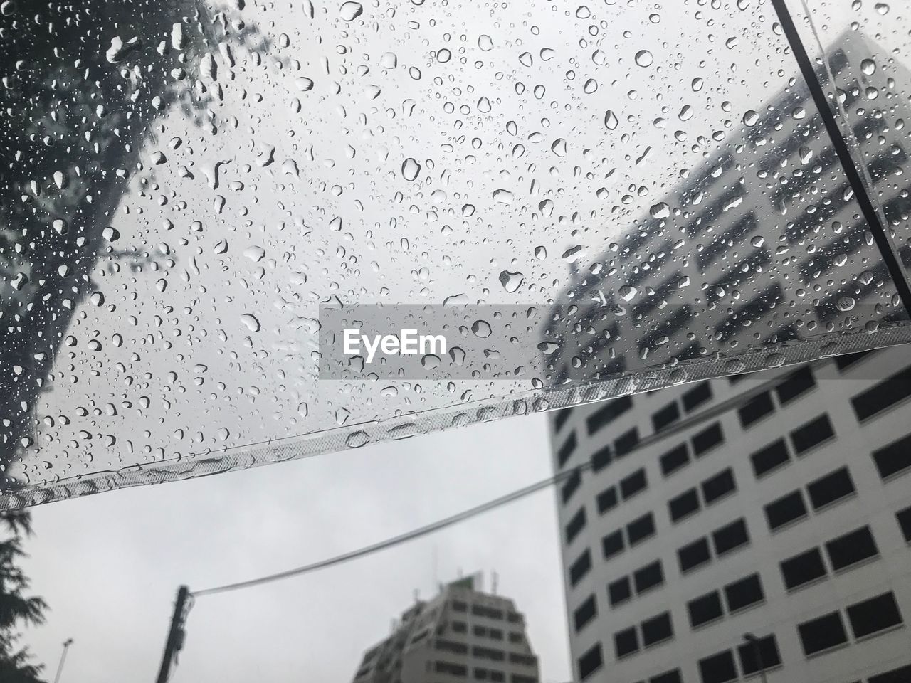 LOW ANGLE VIEW OF BUILDINGS SEEN THROUGH WET GLASS