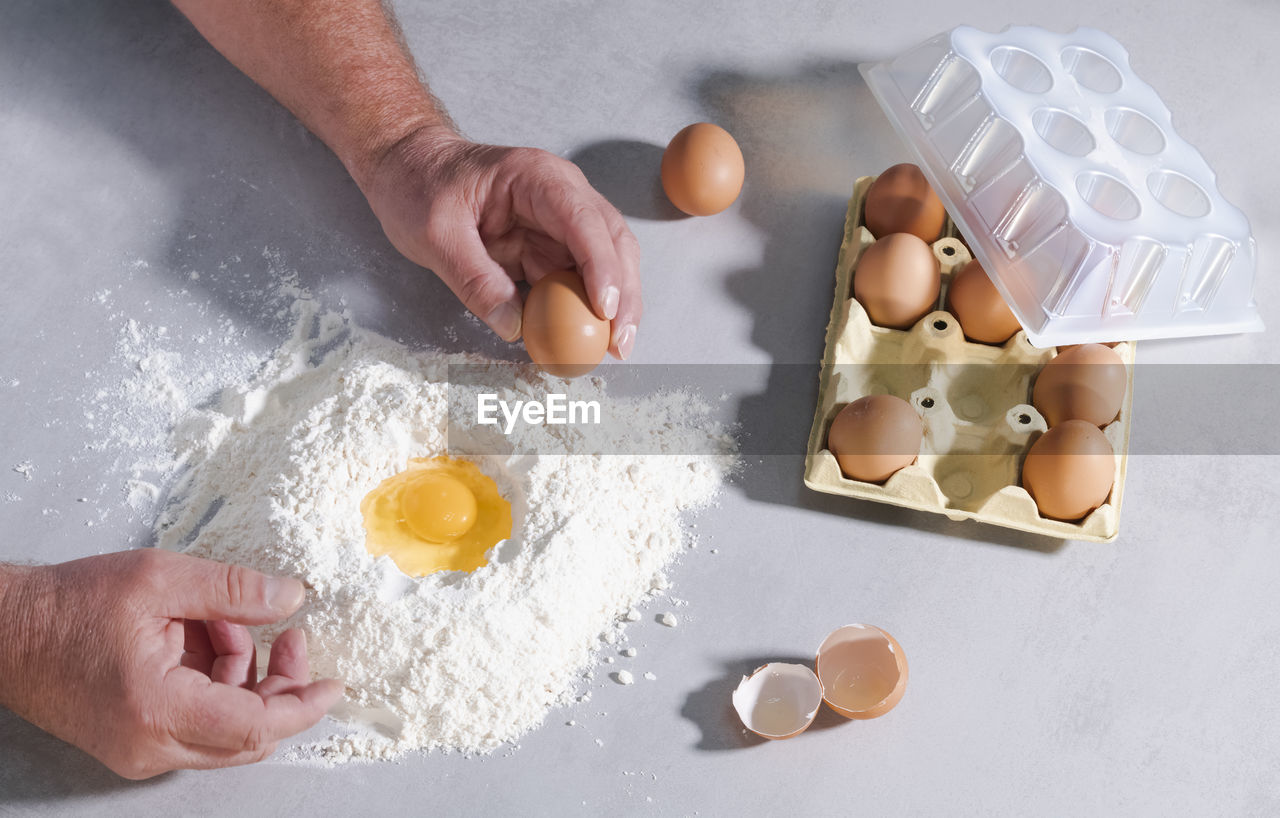 HIGH ANGLE VIEW OF HANDS PREPARING FOOD