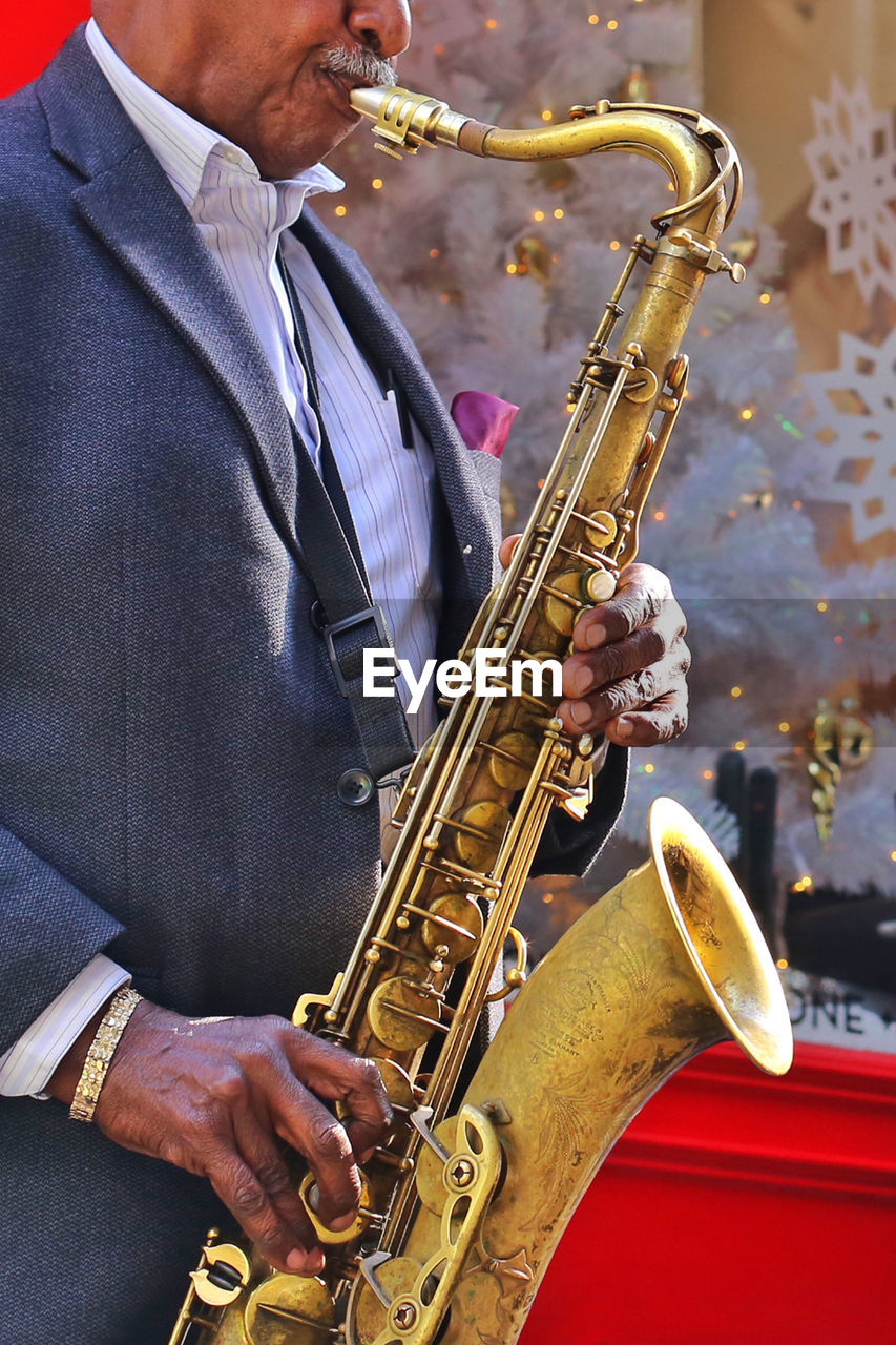 Midsection of senior male musician playing saxophone outdoors