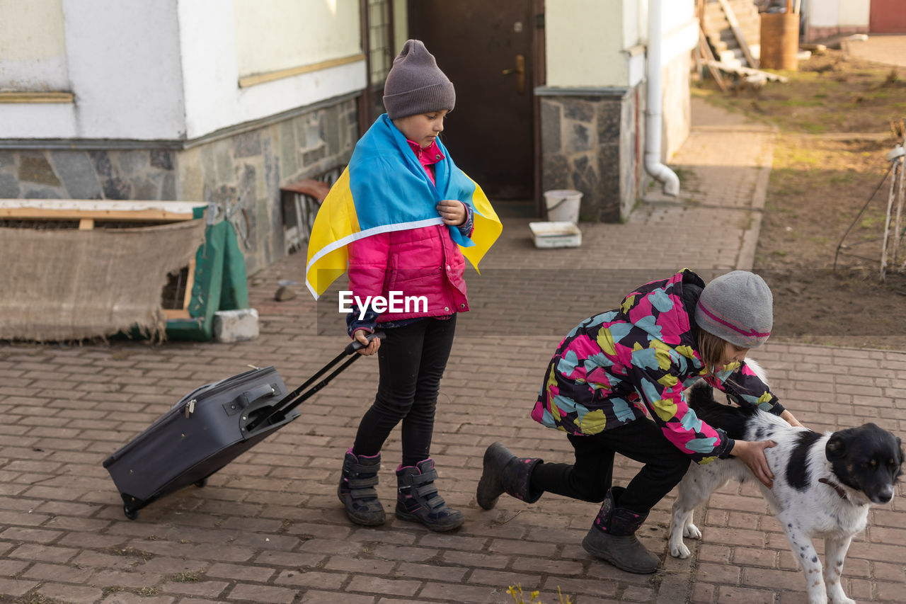 Ukraine military migration. two little girls with a suitcase. flag of ukraine, help. 